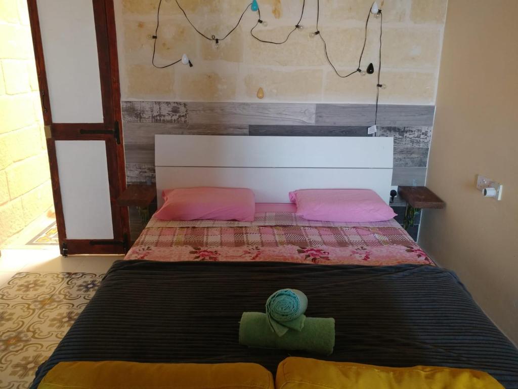 - un lit avec des oreillers roses et verts dans l'établissement Triesti Home, à Victoria
