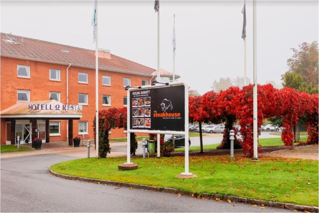 een bord in het gras voor een gebouw bij First Hotel Olofström in Olofström