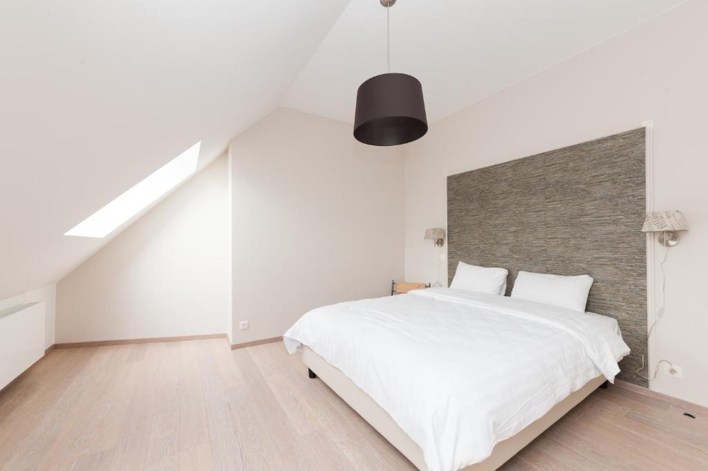a white bedroom with a large bed and a staircase at Smartflats Design - Opera in Liège