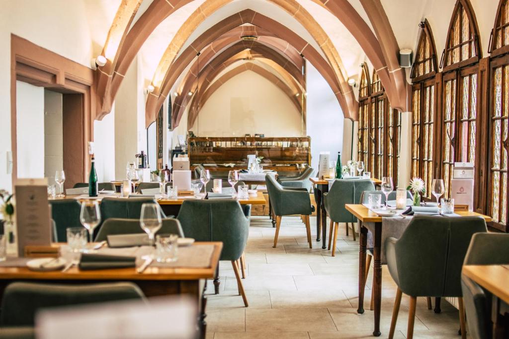 a restaurant with wooden tables and green chairs at Boutiquehotel Kloster Pfalzel in Trier
