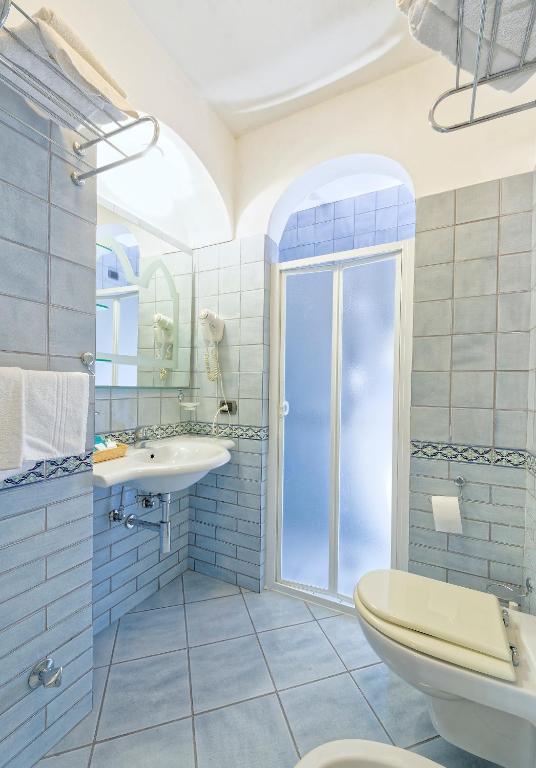 Baño azul con aseo y lavamanos en Hotel Punta Imperatore, en Isquia