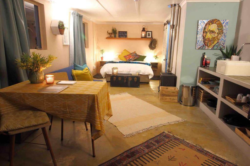ein Wohnzimmer mit einem Tisch und einem Bett in der Unterkunft Starry Starry Night in Montagu