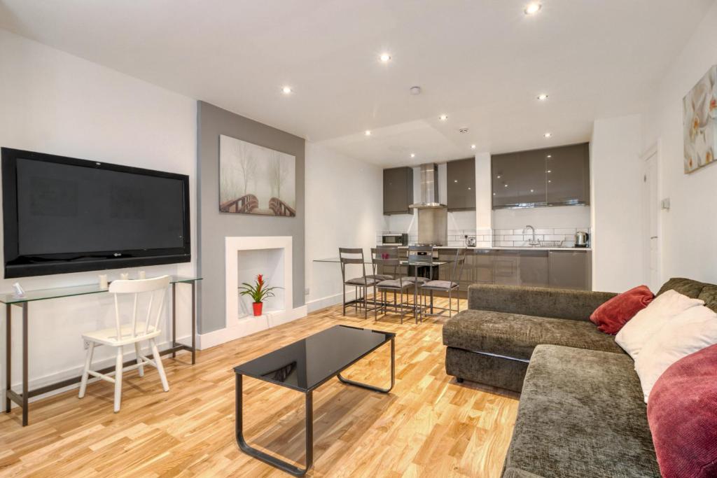 Una sala de estar con un sofá y un televisor. en Holland Park Apartment, en Londres