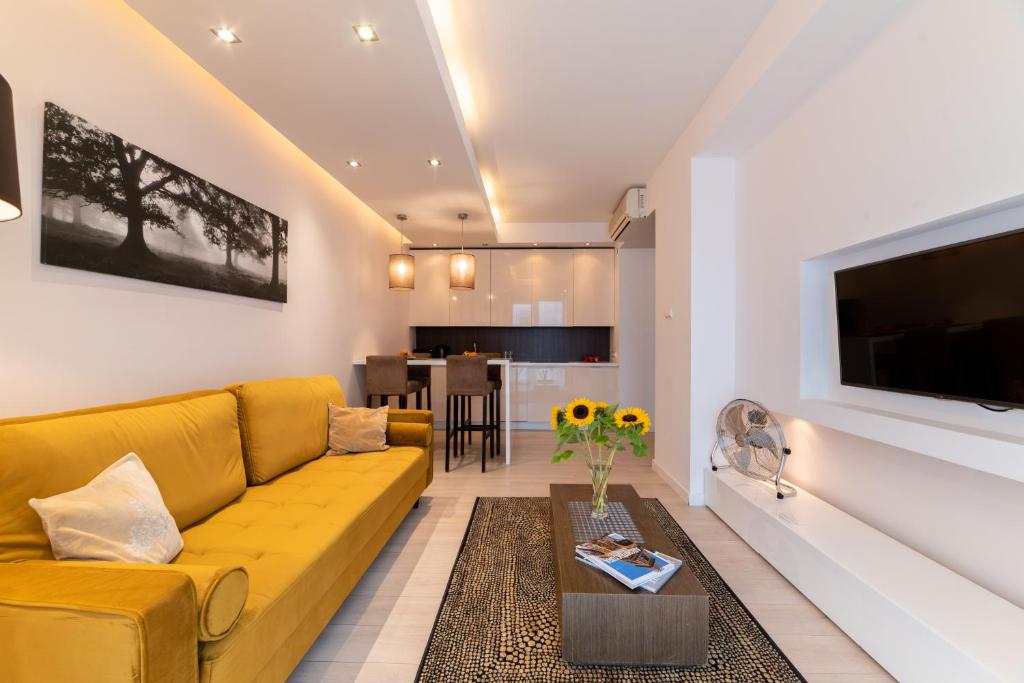 ein Wohnzimmer mit einem gelben Sofa und einem Tisch in der Unterkunft Platinum Towers E-Apartments in Warschau