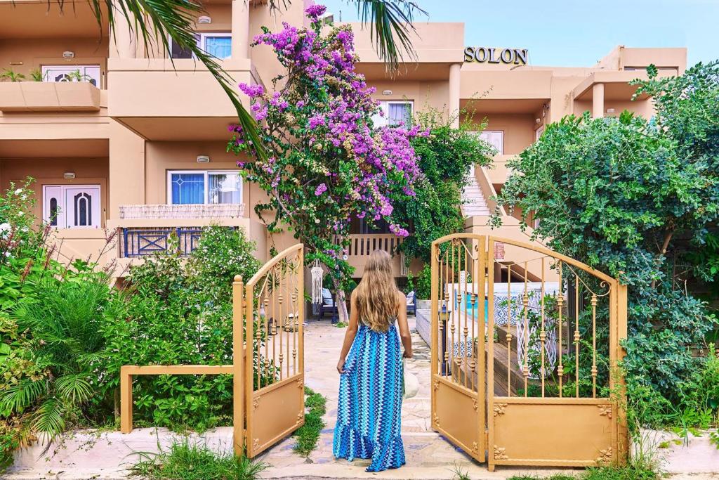 una mujer caminando por una puerta delante de un edificio en Solon Apartments en Maleme