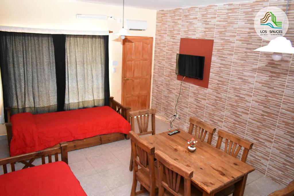 Sala de estar con cama roja y mesa en APART CABAÑAS LOS SAUCES in 