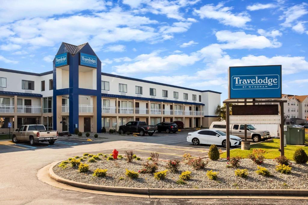 Travelodge by Wyndham Fort Wayne North في فورت واين: مبنى كبير مع وجود لافته في موقف السيارات