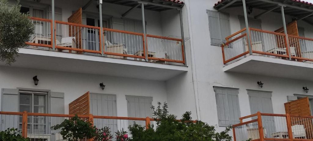 an apartment building with orange balconies and chairs at Skalopati Studios & Villa in Panormos Skopelos