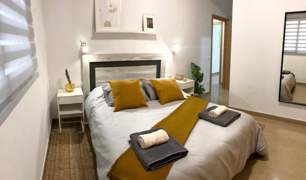 una camera da letto con un grande letto bianco con cuscini gialli di Natura Apartments a Chelva