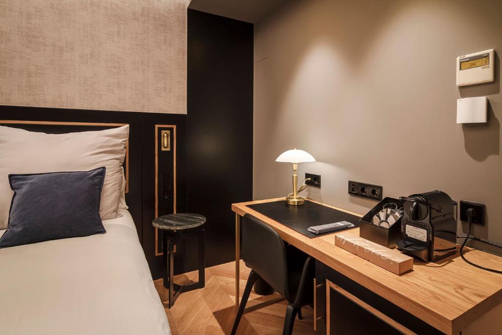 um quarto com uma cama e uma secretária com um telefone em IBIZA ROOMs em Logroño