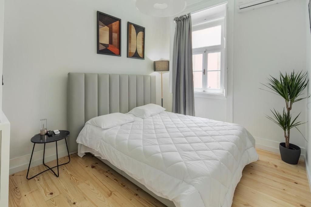 ein weißes Schlafzimmer mit einem Bett und einem Fenster in der Unterkunft Petit studio Rosa - Bairro Alto in Lissabon