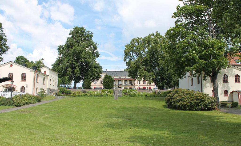 un ampio cortile erboso di fronte a un edificio di Lindesbergs Stadshotell a Lindesberg