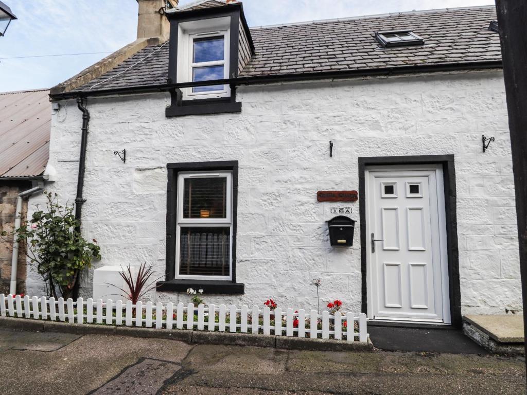 a white house with a white door and a fence at Griffin Cottage in Nairn