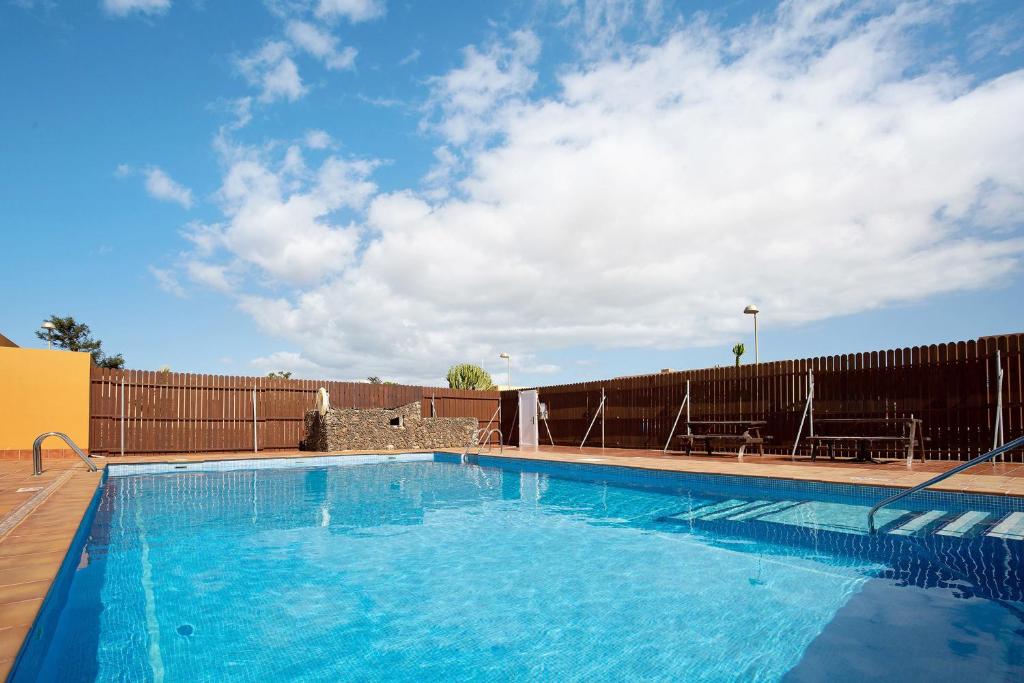 una gran piscina azul junto a una valla en Villa Dayely, en Corralejo