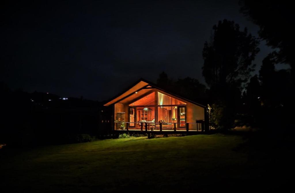 una casa iluminada por la noche con las luces encendidas en Casa Bauda de Chiloé en Castro