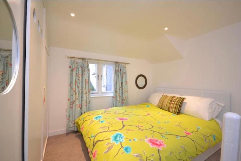 ein Schlafzimmer mit einem gelben Bett und einem Fenster in der Unterkunft Compact, central apartment, dog friendly. in Kingsbridge