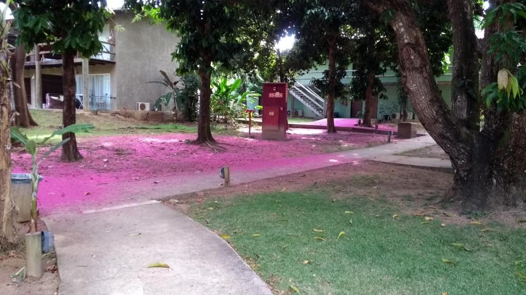 a park with pink flowers in front of a building at Bangalô no alto da colina no Villas do Pratagy - Maceió in Maceió