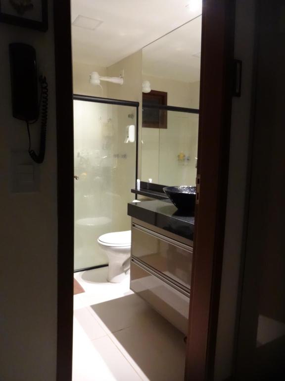 a bathroom with a toilet and a sink and a mirror at Bangalô no alto da colina no Villas do Pratagy - Maceió in Maceió