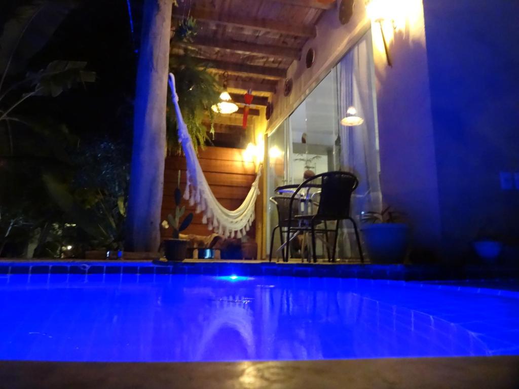 a swimming pool at night with blue lights at Bangalô no alto da colina no Villas do Pratagy - Maceió in Maceió
