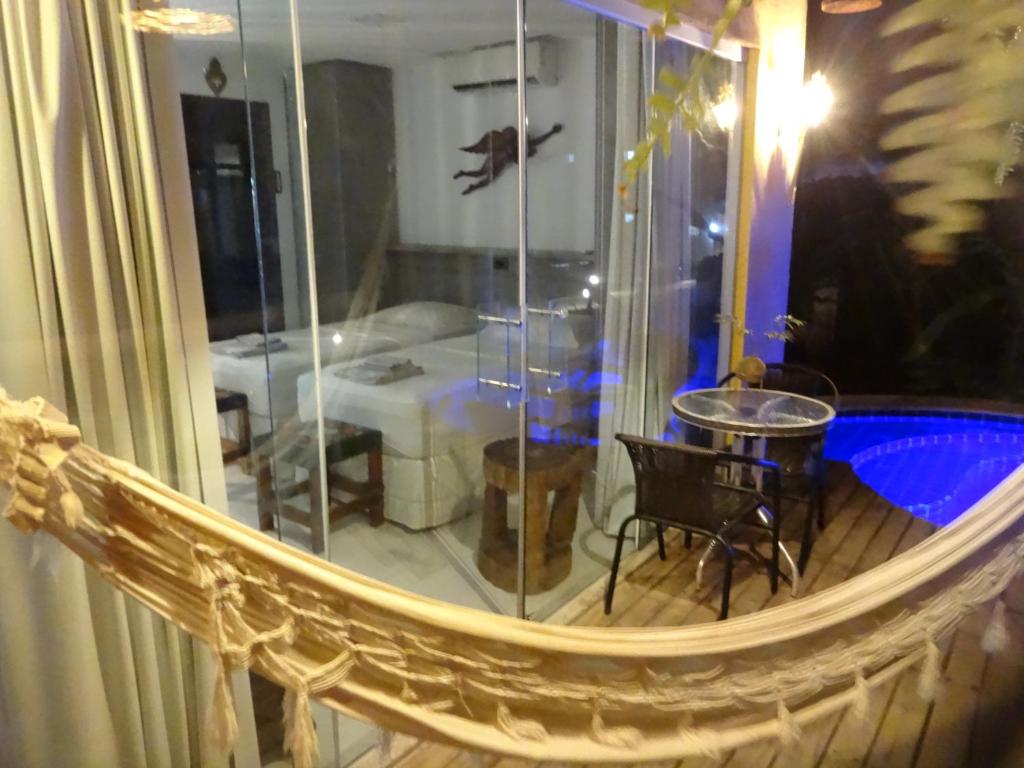 a room with a balcony with a table and a room with at Bangalô no alto da colina no Villas do Pratagy - Maceió in Maceió