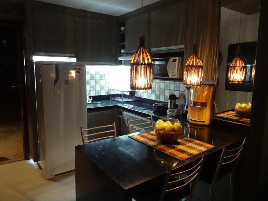 a kitchen with a table with a bowl of fruit on it at Bangalô no alto da colina no Villas do Pratagy - Maceió in Maceió