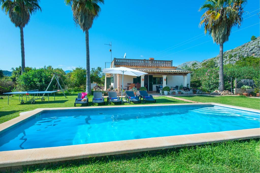 a swimming pool in front of a house with palm trees at Owl Booking Villa Punta Magdalena - Family Holidays in Pollença