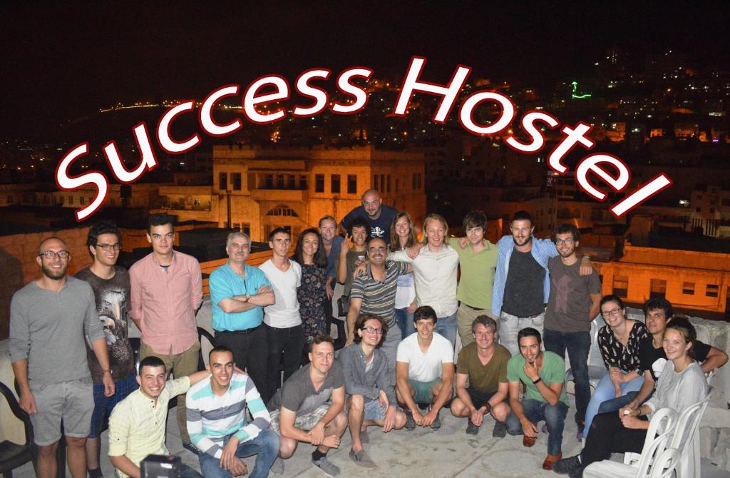 un grupo de personas posando para una foto delante de un cartel en Success Hostel, en Nablus