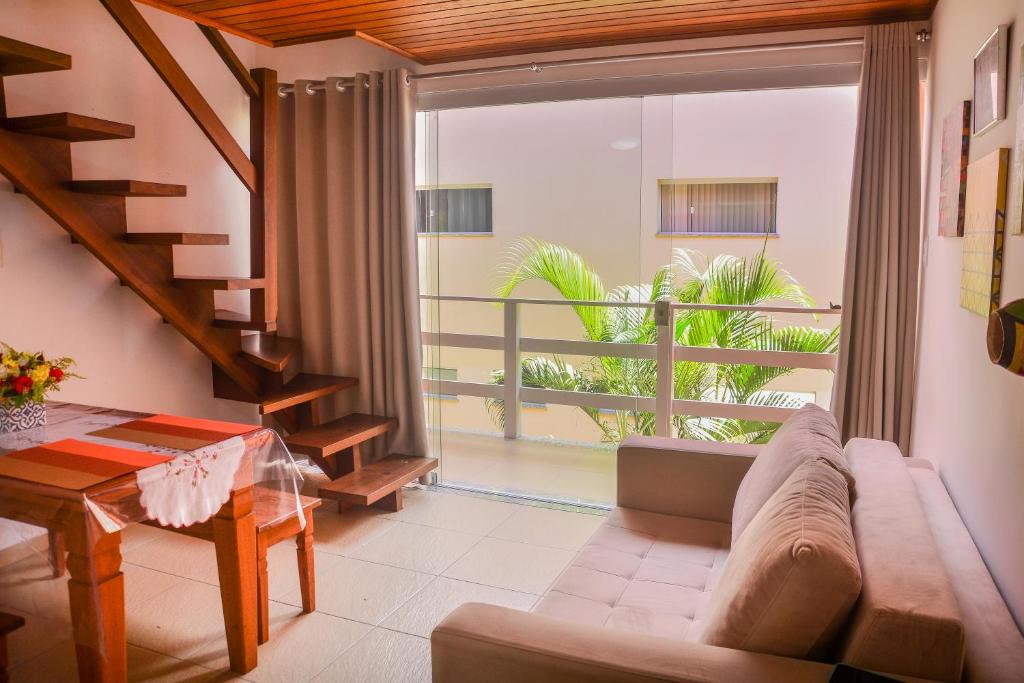 a living room with a couch and a large window at Flat AGC in Morro de São Paulo