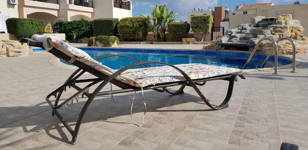 uma cama de metal em frente a uma piscina em Petras Cozy Nest, 1-bedroom apt., Paphos-Universal em Paphos