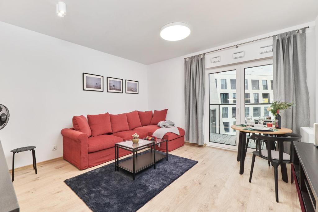 a living room with a red couch and tables at Studio Księcia Witolda 32 by Renters in Wrocław