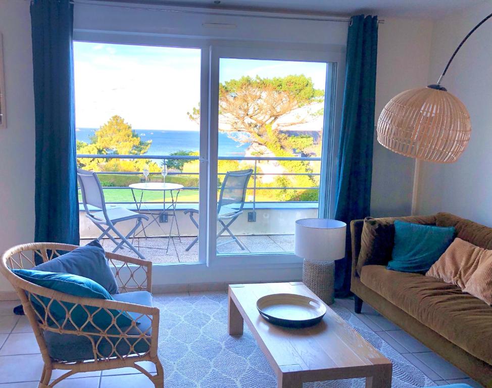 uma sala de estar com um sofá e vista para o oceano em Appartement vue mer à 100m de la plage au centre de Carantec em Carantec