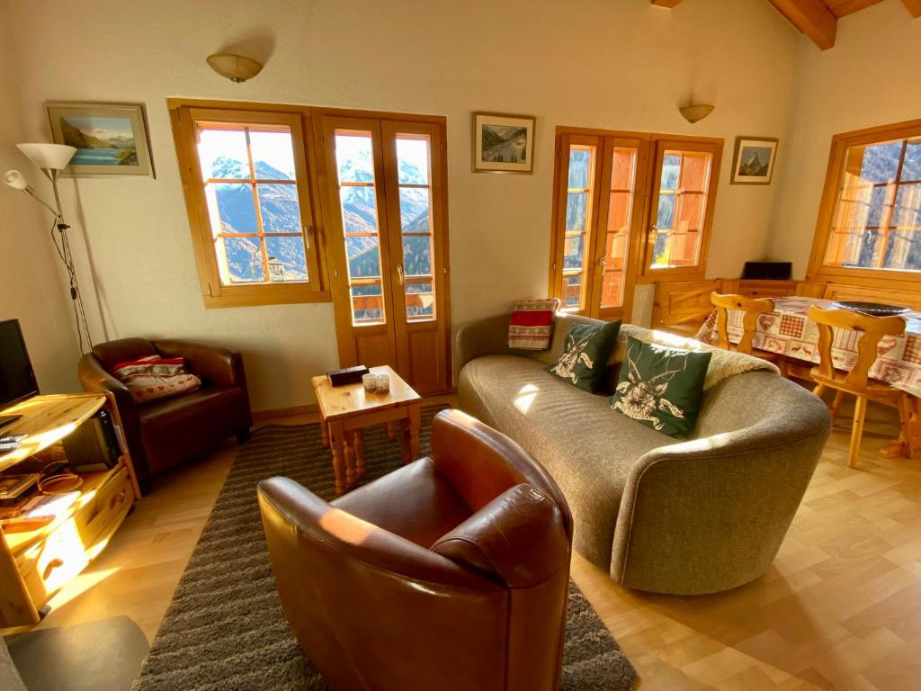 ein Wohnzimmer mit einem Sofa, Stühlen und einem Tisch in der Unterkunft Chalet Amos in Grimentz