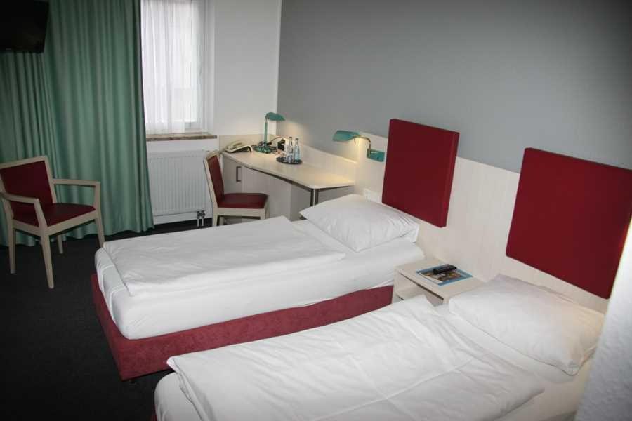 a hotel room with two beds and a table and a desk at Vorsfelder Hof in Wolfsburg