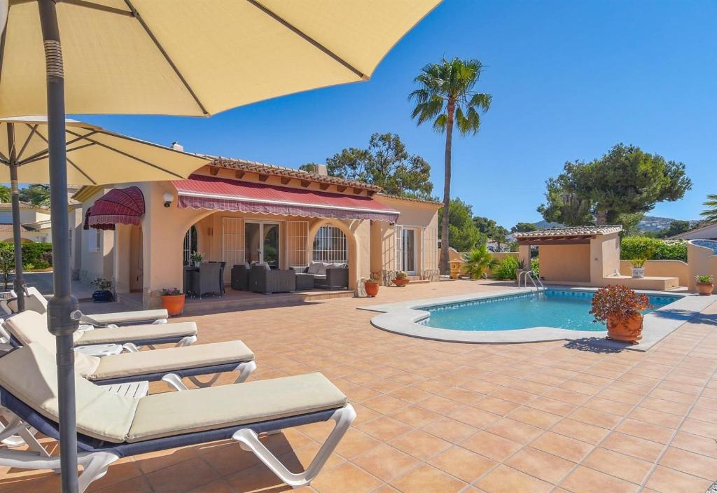 een terras met stoelen en een parasol en een zwembad bij Casa Siempre Domingo in Moraira