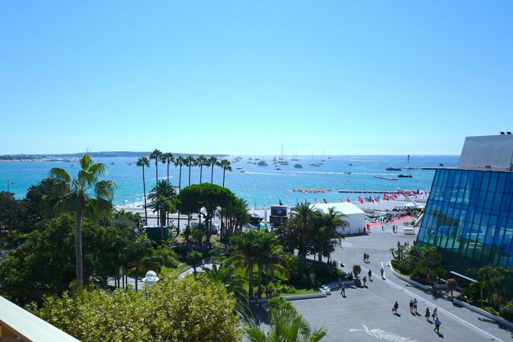 uma vista para uma praia com palmeiras e para o oceano em Cannes - Croisette - Palais des Festivals em Cannes