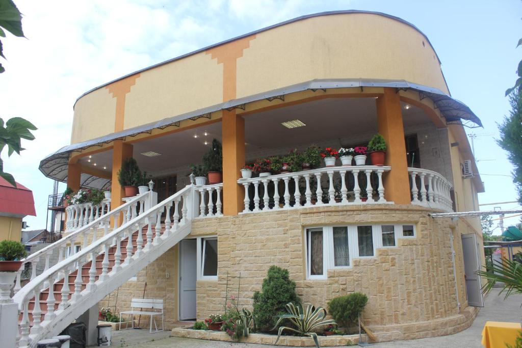 a building with a balcony with flowers on it at Esenya Guest House in Adler