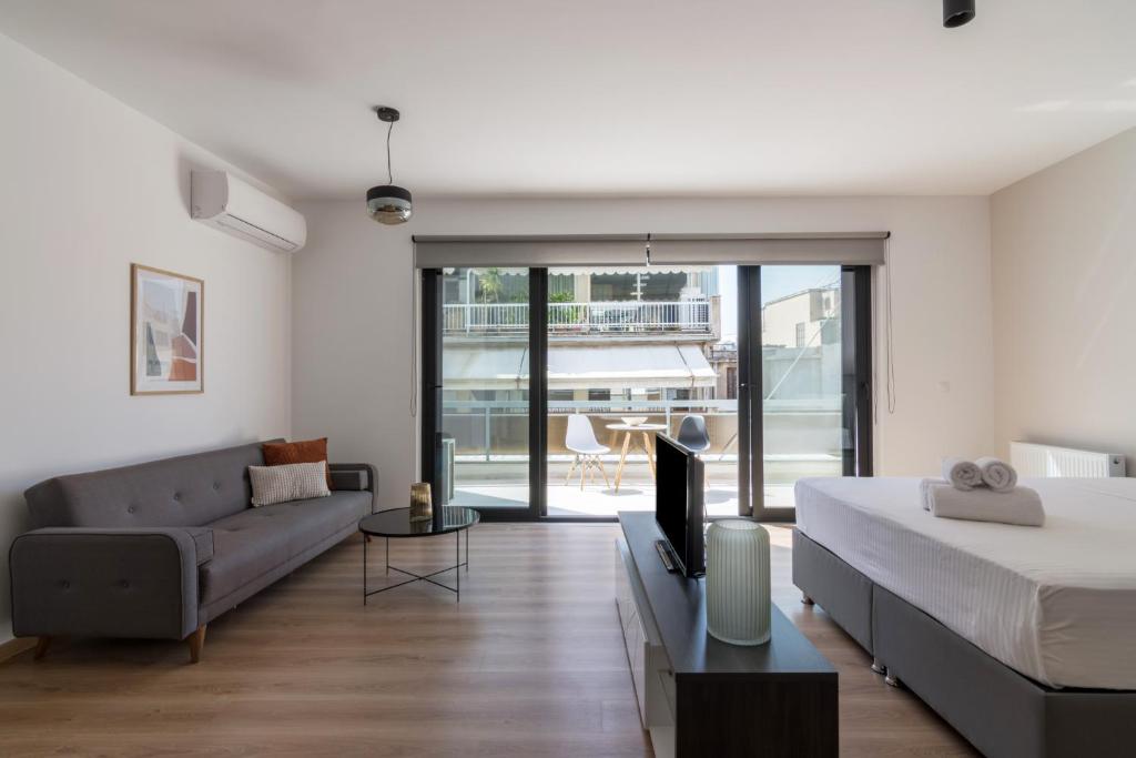雅典Leochares Lifestyle Apartments - Self check-in的一间带床、沙发和电视的卧室
