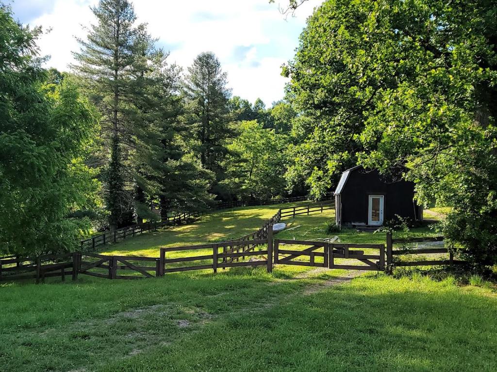een houten hek en een schuur in een veld bij Rustic Farm Stay in a Hendersonville Studio! in Hendersonville