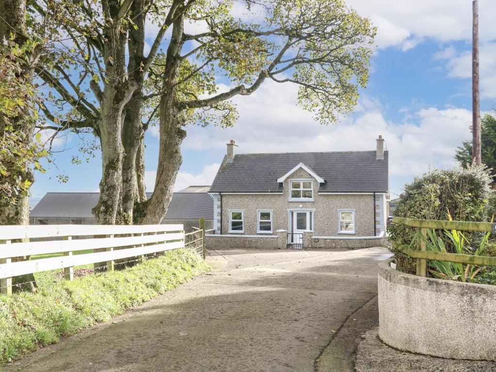 a house with a white fence and a tree at Granny's in Bushmills