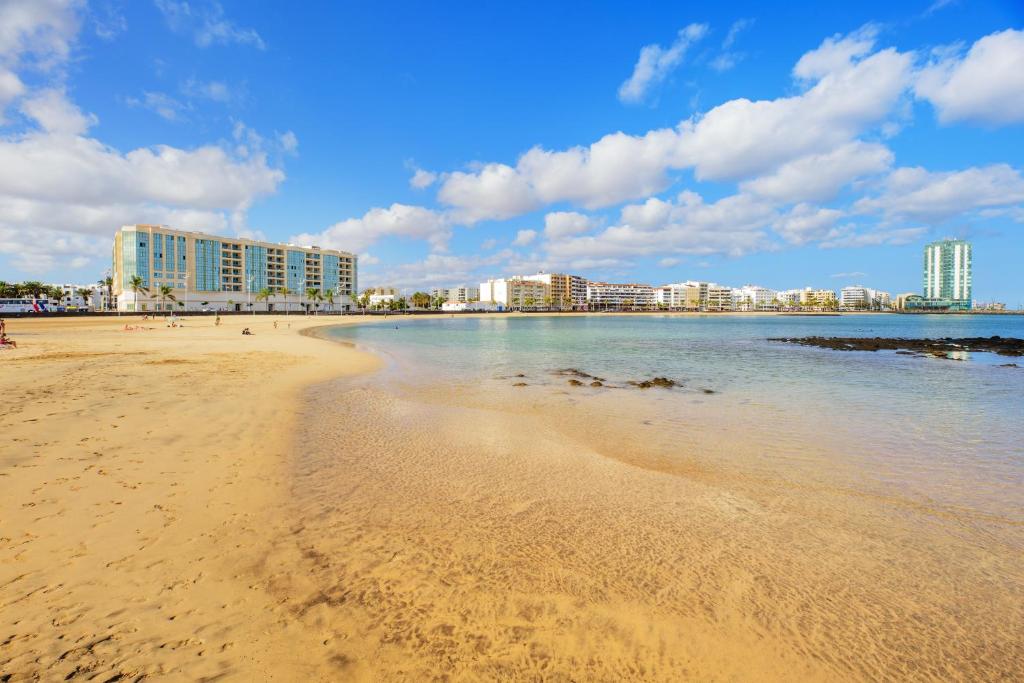 a sandy beach with buildings in the background at Lanzahost Oceanis XXI in Arrecife