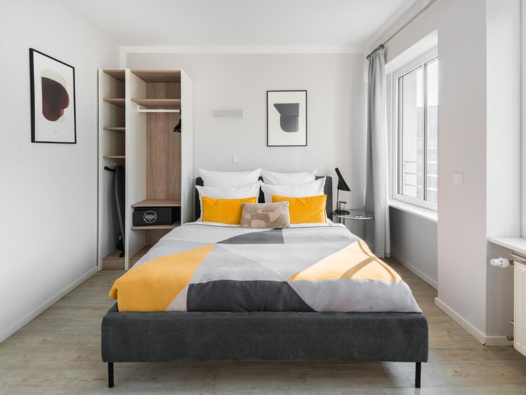 a bedroom with a large bed with yellow pillows at numa I Blau Apartments in Frankfurt/Main