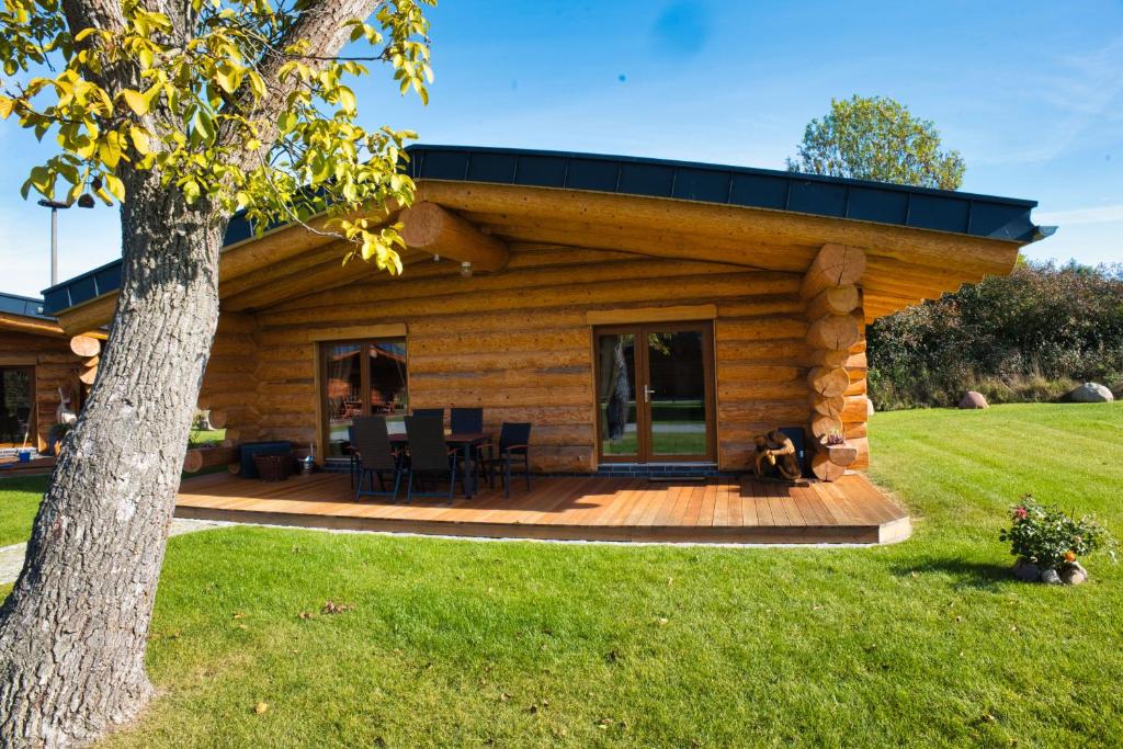 a log cabin with a dog sitting on a deck at Ferienidyll zur Spreeaue in Briesen