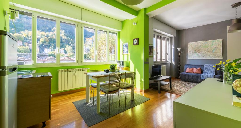 uma cozinha com paredes verdes e uma mesa e cadeiras em JOIVY Vibrant Studio Near Train Station em Como