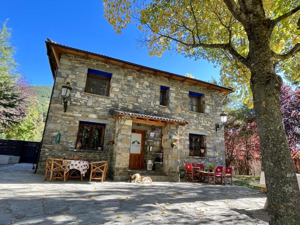 una casa de piedra con un perro tirado frente a ella en Rural Hostel dos Lucas en Biescas