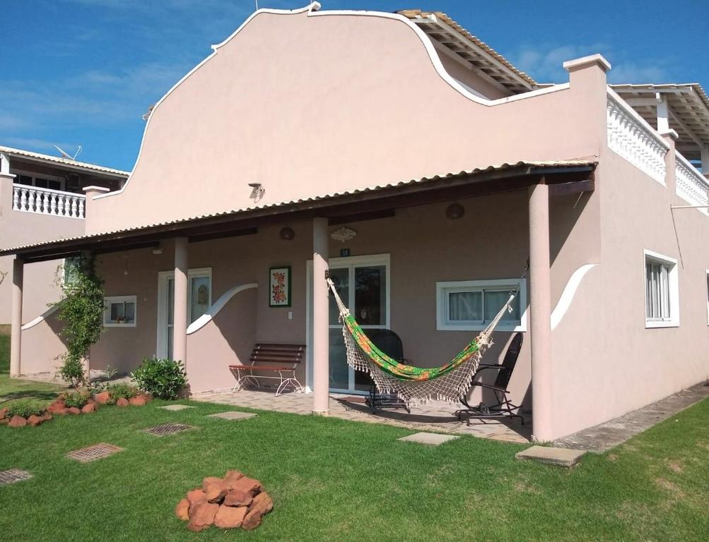 a pink house with a hammock in the yard at Casa Eco Fiore 58 in Paripueira