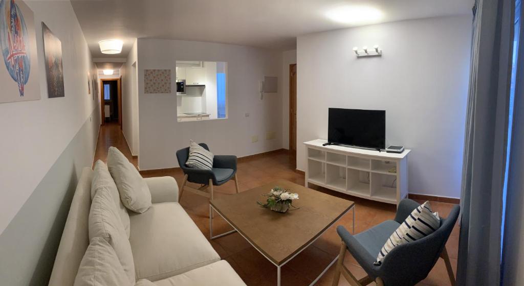 Una sala de estar con un sofá y sillas y un televisor. en VIANYMAR APARTAMENTOS, en El Médano