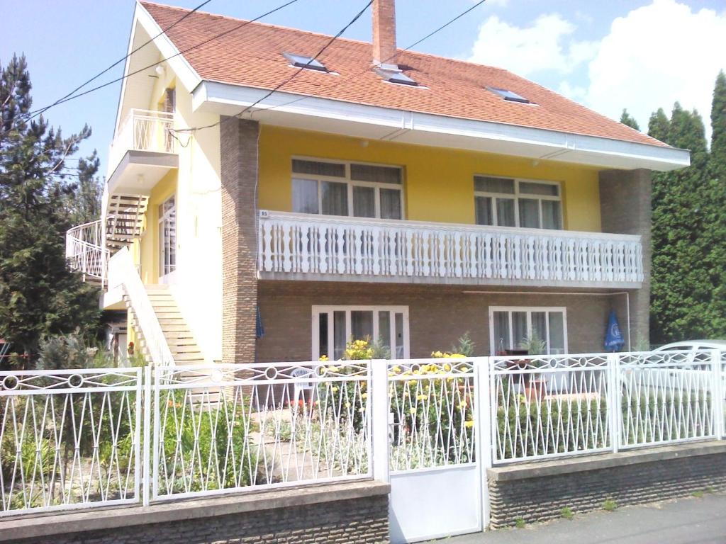 a house with a white fence in front of it at Napfény Apartment in Keszthely