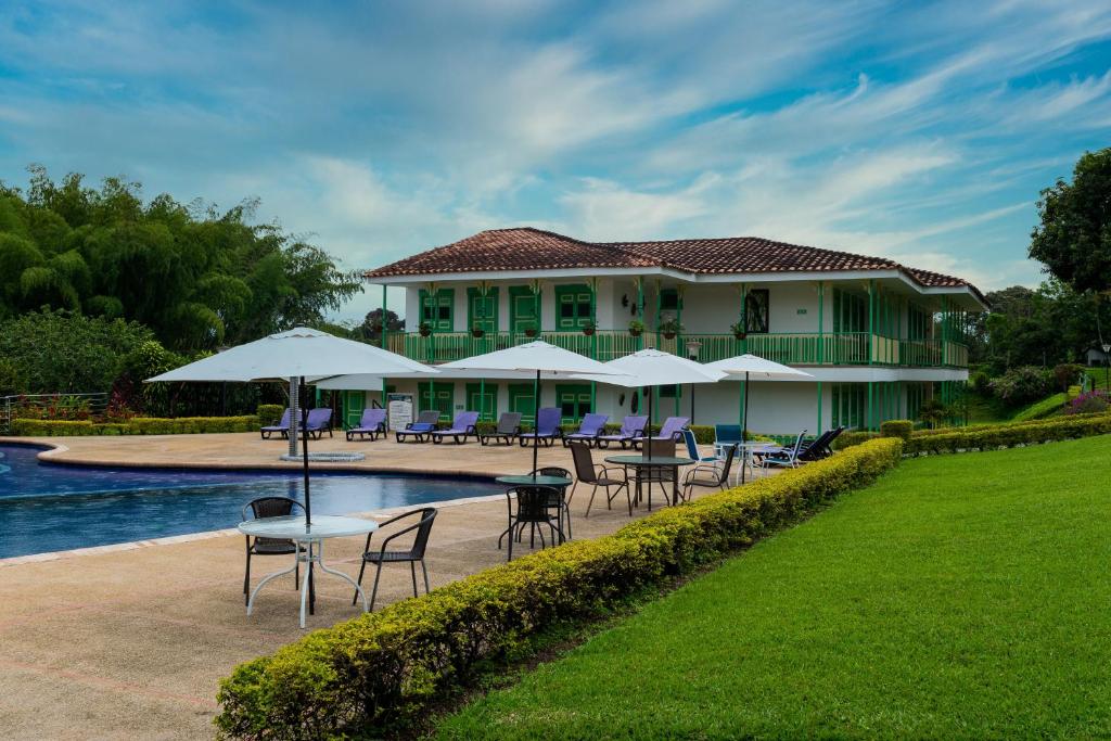 a resort with tables and chairs and a pool at Hotel Eden Parque del Cafe in Montenegro