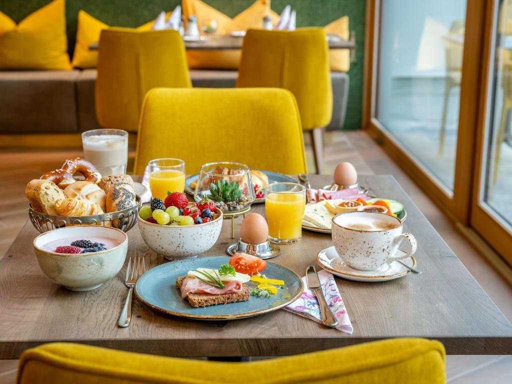 a table with breakfast foods and cups of orange juice at Hotel FrechDachs in Bad Füssing