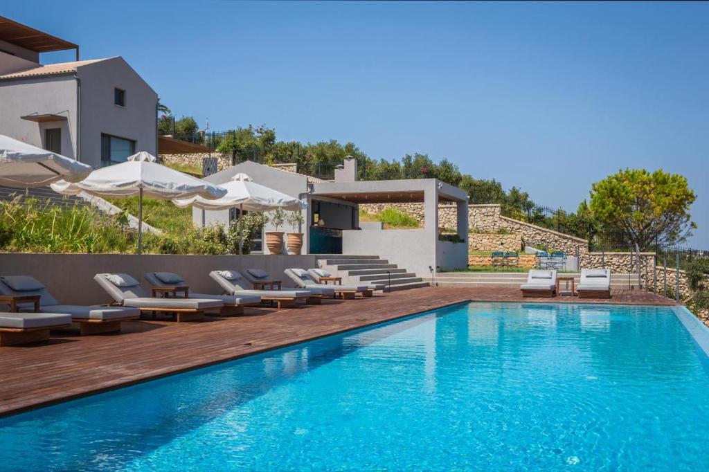 a swimming pool with chairs and a house at Harmony Suites in Khelmáta